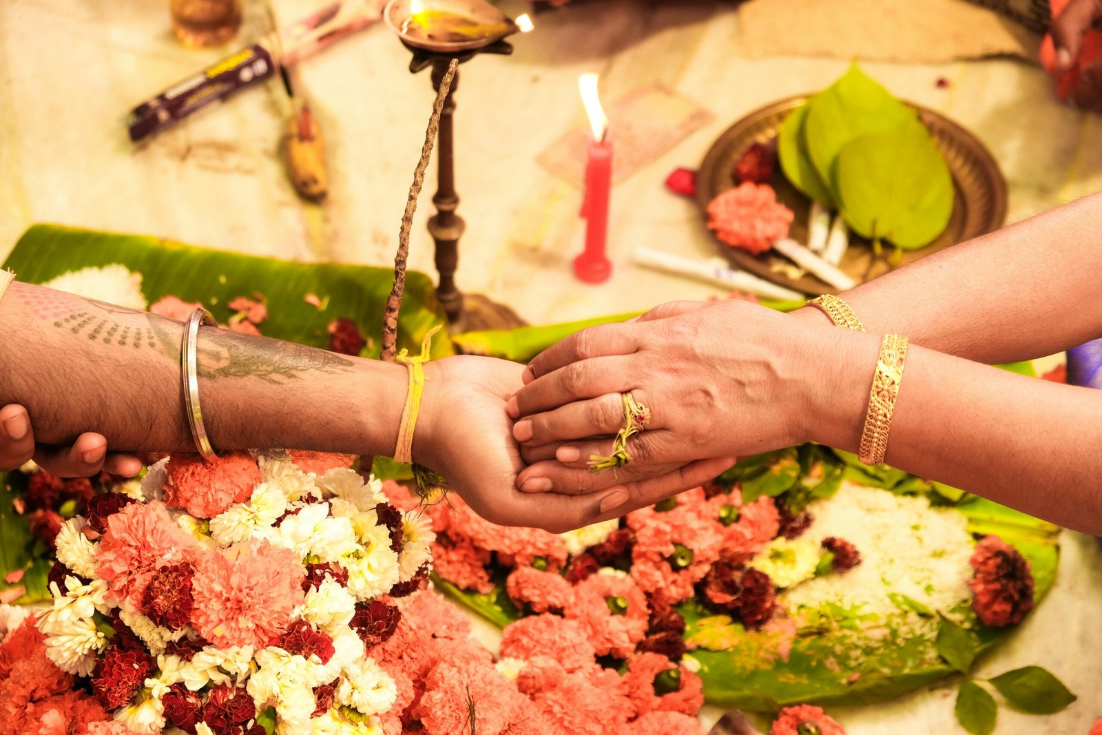 Close-up of a traditional Indian wedding ritual with hands and vibrant flowers.